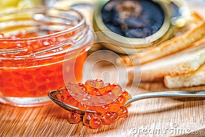 Red caviar and caviar. Spoon of red caviar and open cans of cavi