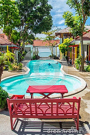 Red chair and table on edge of swimming pool.