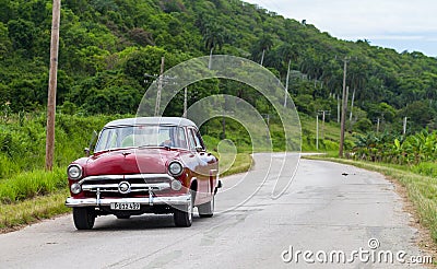 A red classic car drived on the road