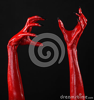 Red Devil s hands with black nails, red hands of Satan, Halloween theme, on a black background, isolated