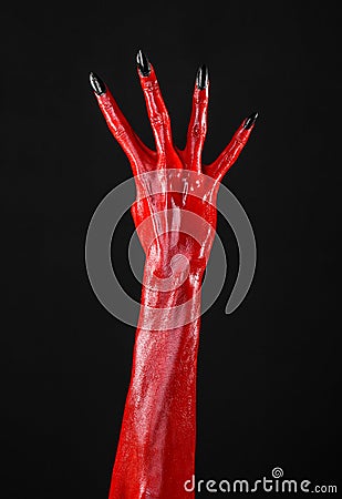 Red Devil s hands with black nails, red hands of Satan, Halloween theme, on a black background, isolated