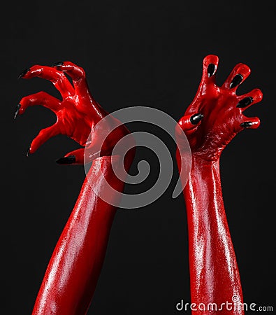 Red Devil s hands with black nails, red hands of Satan, Halloween theme, on a black background, isolated