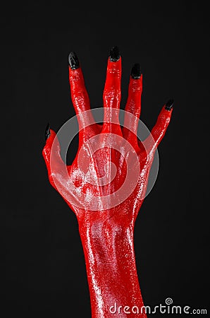 Red Devil s hands with black nails, red hands of Satan, Halloween theme, on a black background, isolated