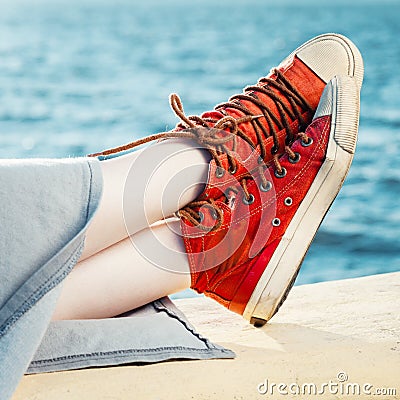 Red fashion sneakers on girl and sea landscape