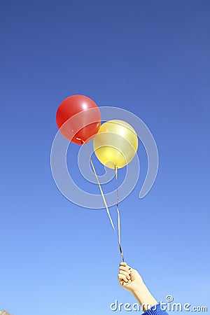 Red and gold air balloons in hand on blue sky background