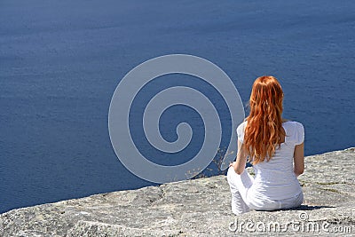 Red-haired girl looking over blue water