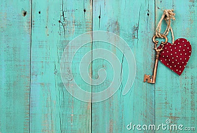 Red heart and bronze skeleton key hanging on antique green wood door