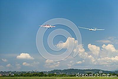 Red motor airplane tows glider up in the air