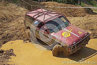 Red off road car passing in muddy puddles