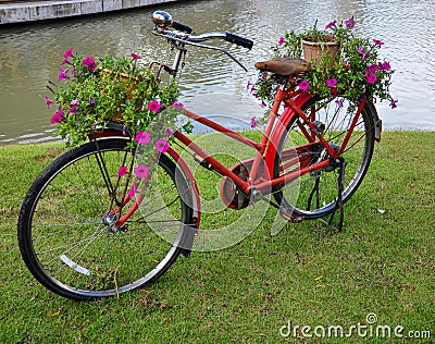 Red painted bicycle with a bucket of colorful flowers