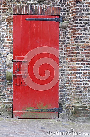 Red painted door with heavy security bolts and brick wall