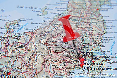 Red pin pointing Tokyo on map in atlas