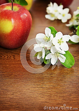 Red ripe apple fruit and apple flower on a wooden table