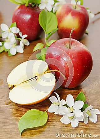 Red ripe apple fruits and apple flower on a wooden table