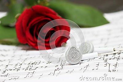 Red rose, earphones, piano sheet music