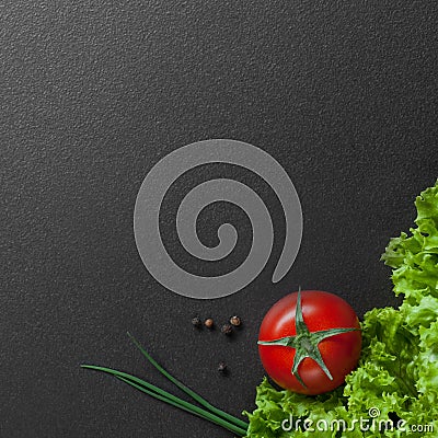 Red tomato with green salad on black