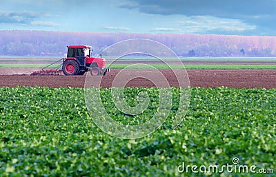 Red tractor working on thre agricultural field