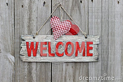 Red welcome sign hanging on wood door with gingham heart