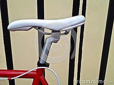 Red and white racing bike leaning against iron railings.