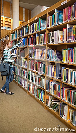 Redhead student taking a book from bookshelf in the library