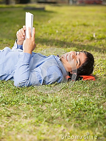 Relaxed Man Holding Book While Lying On Grass At