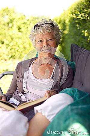 Relaxed old woman reading in backyard