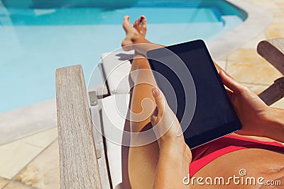 Relaxed woman using digital tablet by the poolside