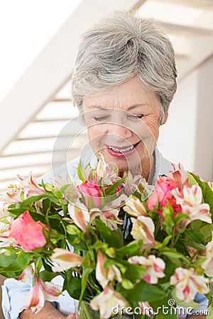 Retired woman holding bouquet of flowers and smiling