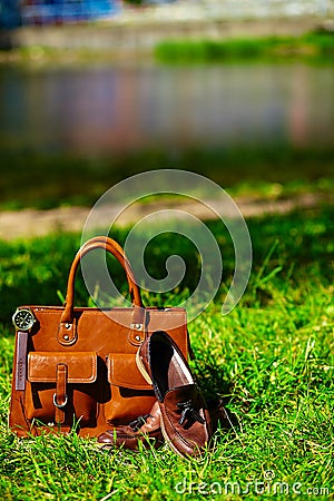 Retro brown shoes and man leather bag in bright colorful summer grass