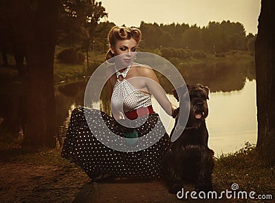 Retro style. The girl with a dog in a park in sunset rays.