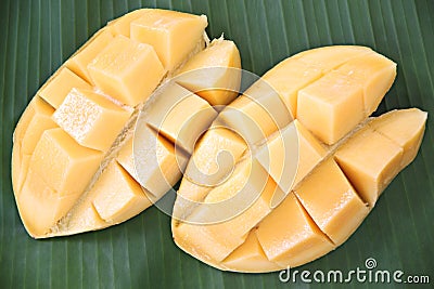 Ripe mango with slices on banana leaves.