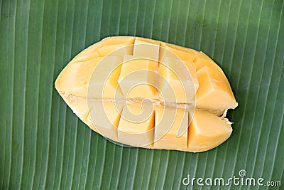 Ripe mango with slices on banana leaves.