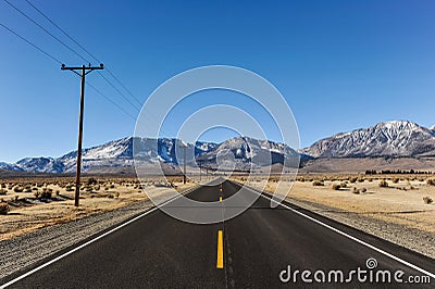 Road to mountains with telephone poles on side