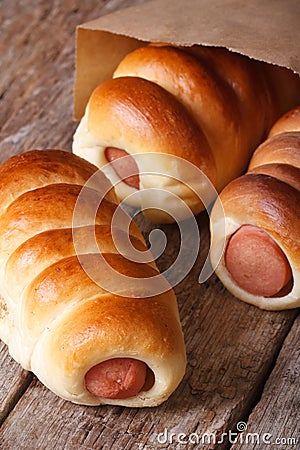 Roll with sausage close up in a paper bag vertical