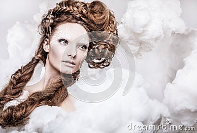 Romantic beauty with magnificent hair wandering in clouds. Studio fashion portrait.