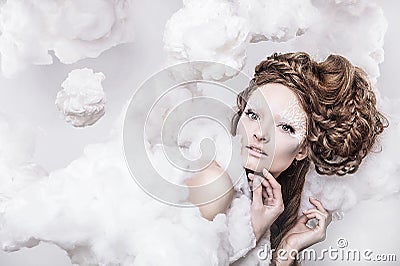 Romantic beauty with magnificent hair wandering in clouds. Studio fashion portrait.