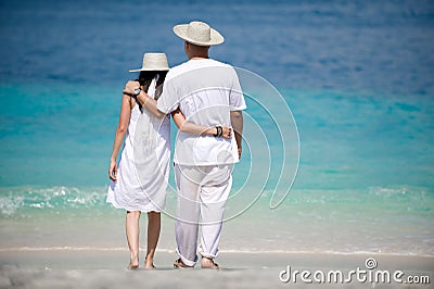 Romantic couple wearing hats on the beach