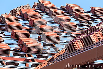 Roof under construction with stacks of roof tiles for home build