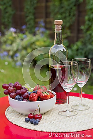 Rose wine with summer fruits on garden table