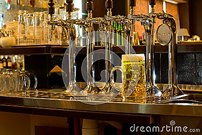 Row of beer taps in a pub with a tankard of beer