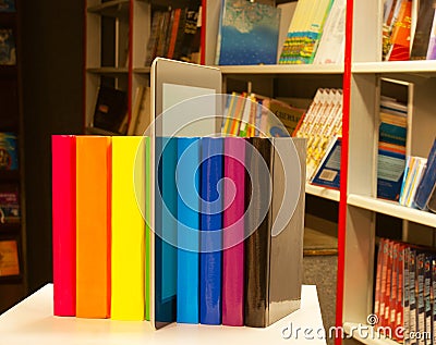 Row of colorful books and tablet PC