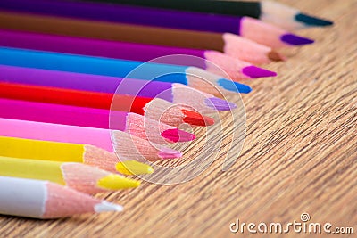 Row of many colorful drawing pencils on wooden table