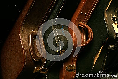 Close-up of a row of stacked, old and worn guitar cases.