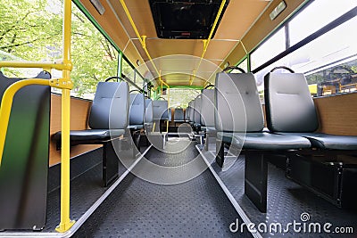 Rows of grey seats inside clear saloon of empty city bus