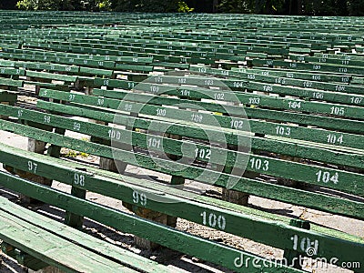 Rows of simple green seats near empty outdoors scene