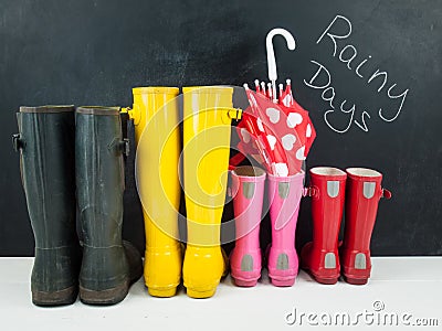 Rubber boots with an umbrella against a blackboar