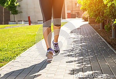 Running woman in black sports outfit (half body photo) on the sidewalk