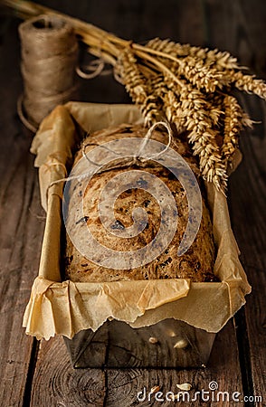 Rustic bread in baking tin and wheat on vintage wood table