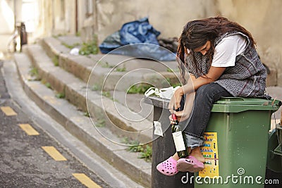 Sad drunk homeless woman on bin