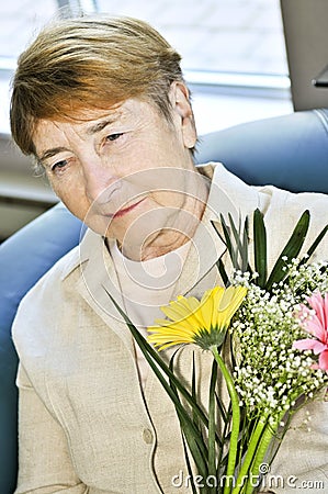 Sad elderly woman with flowers